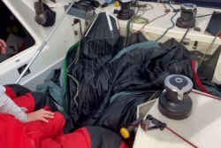 Transat Café L'Or : un voilier couché par le survol d'un avion, sa voile déchirée